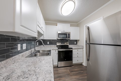 A modern kitchen with a refrigerator, sink, and oven.