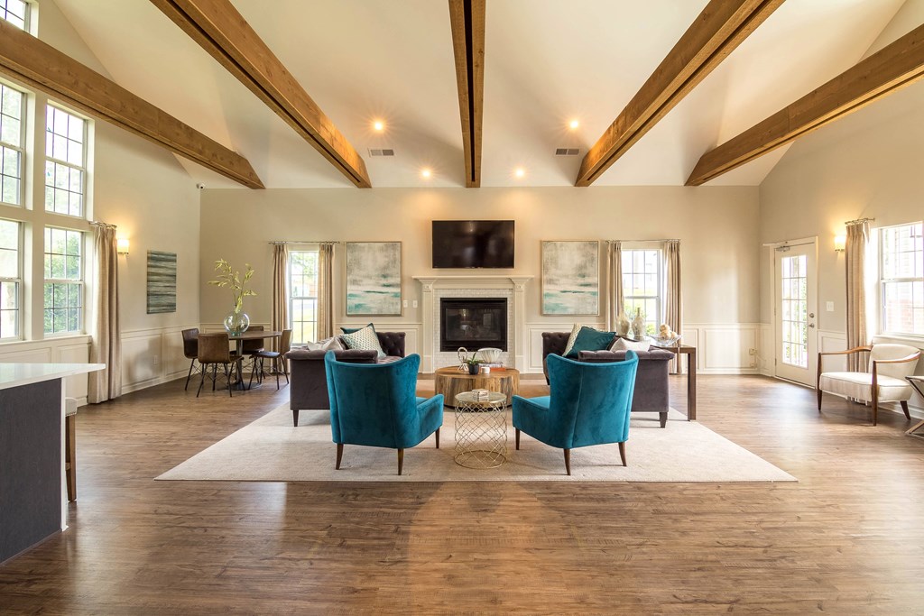 a living room with blue chairs and a fireplace at Abbington Place Apartments, Greensboro , NC 27407