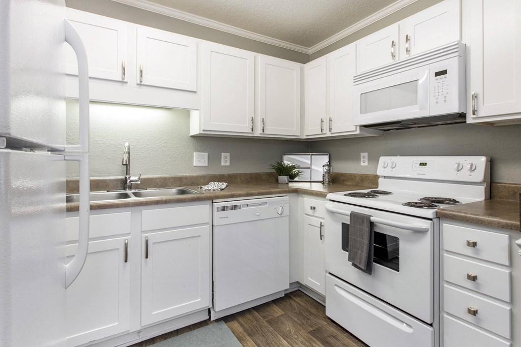 a kitchen with white appliances and white cabinets at Abbington Place Apartments, Greensboro