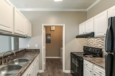 A kitchen with a black stove top oven and white cabinets.