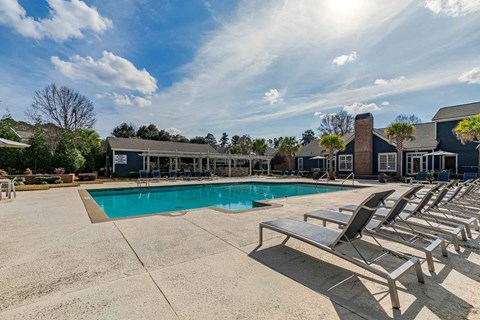 A sunny day at the pool with lounge chairs and a building in the background.