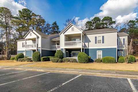 A large two-story apartment building with a parking lot in front.