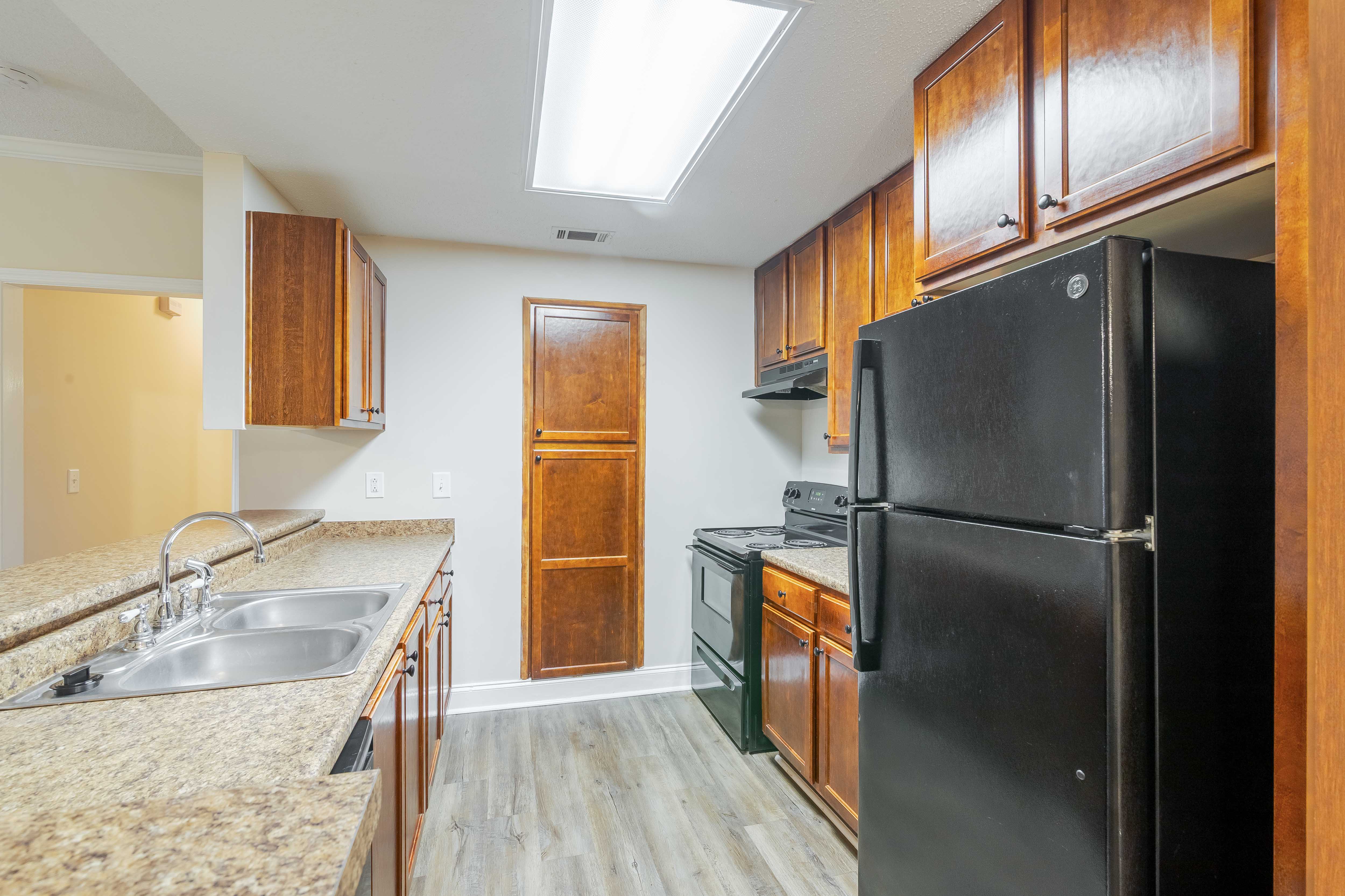A black refrigerator is in a kitchen with wooden cabinets.