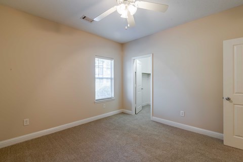 A room with a carpeted floor and a ceiling fan.
