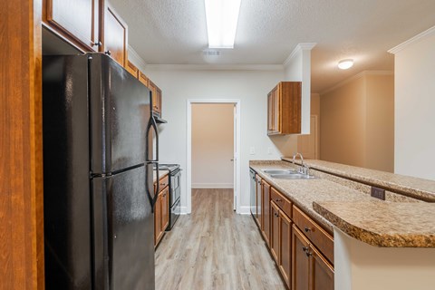 A kitchen with a black refrigerator and wooden cabinets.