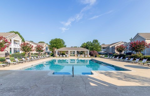 A large swimming pool surrounded by lounge chairs and umbrellas.
