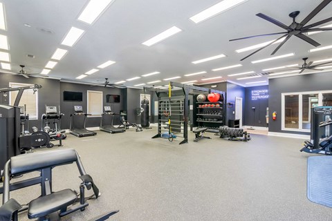 A spacious gym with various exercise equipment and a ceiling fan.