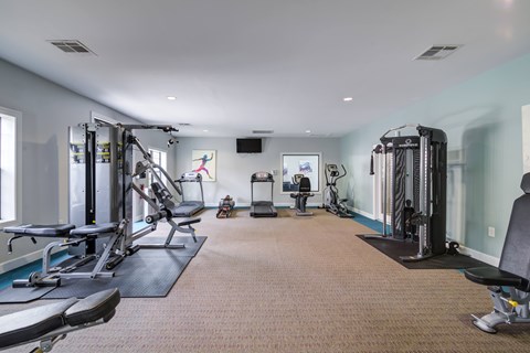 A spacious gym with a variety of equipment including treadmills, weight machines, and benches.