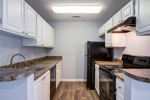 A kitchen with black appliances and white cabinets.