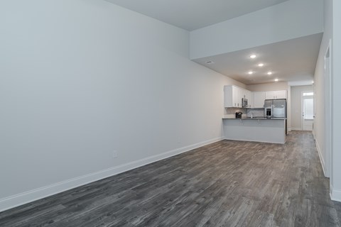 A kitchen with white cabinets and a refrigerator is visible in the background.