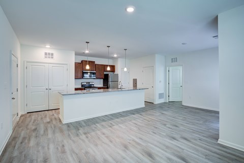 A spacious kitchen with white cabinets and a wooden floor.