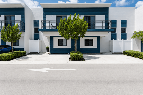 A white and blue building with a tree in front.