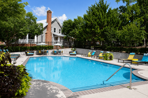 A large swimming pool surrounded by trees and chairs.