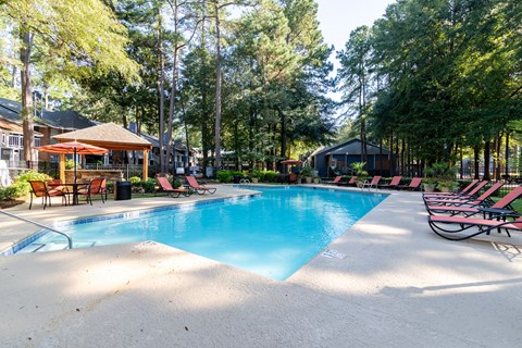 A large swimming pool surrounded by trees and lounge chairs.