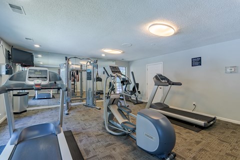 A gym with a variety of equipment including treadmills, weights, and exercise machines.