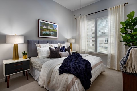 A bedroom with a bed, nightstand, and a painting on the wall.