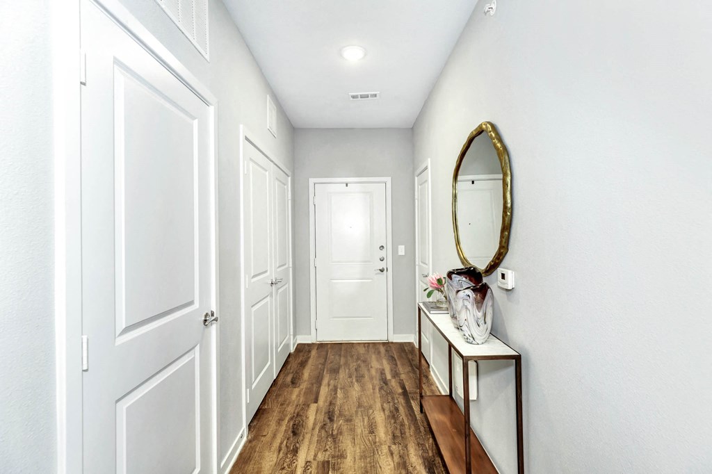 a hallway with white walls and white doors and a mirror at Farmhaus Apartments, Madison