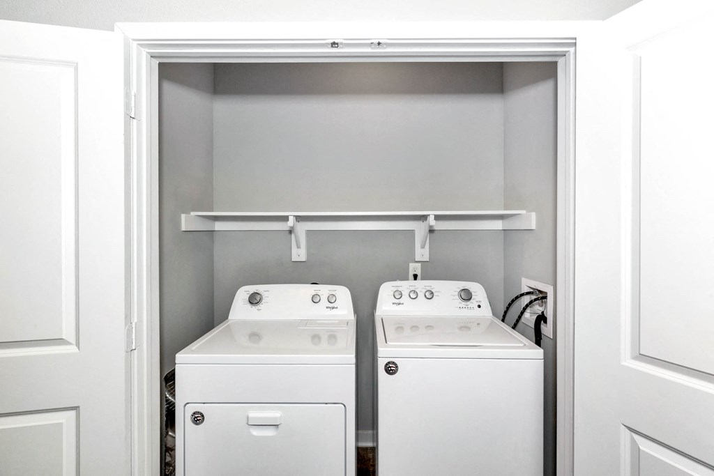 a white laundry room with two washes and a dryer at Farmhaus Apartments, Alabama