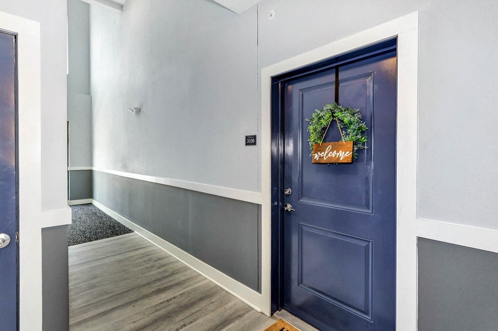 a hallway with a blue door with a wreath on it at Farmhaus Apartments, Madison, AL