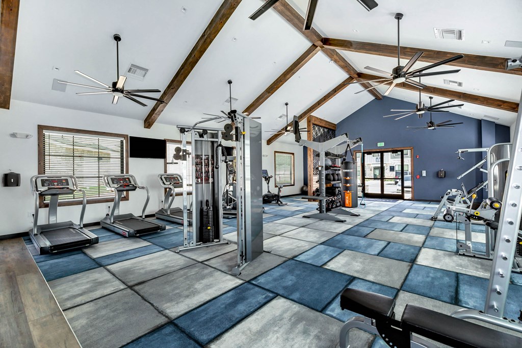 a gym with weights and cardio equipment and a ceiling with wooden beams at Farmhaus Apartments, Madison, AL, 35757
