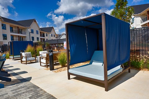 an outdoor lounge area with a blue tent in front of an apartment building at Farmhaus Apartments, Madison, Alabama