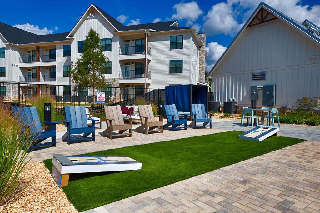 a patio with chairs and a table in front of an apartment building at Farmhaus Apartments, Madison, AL