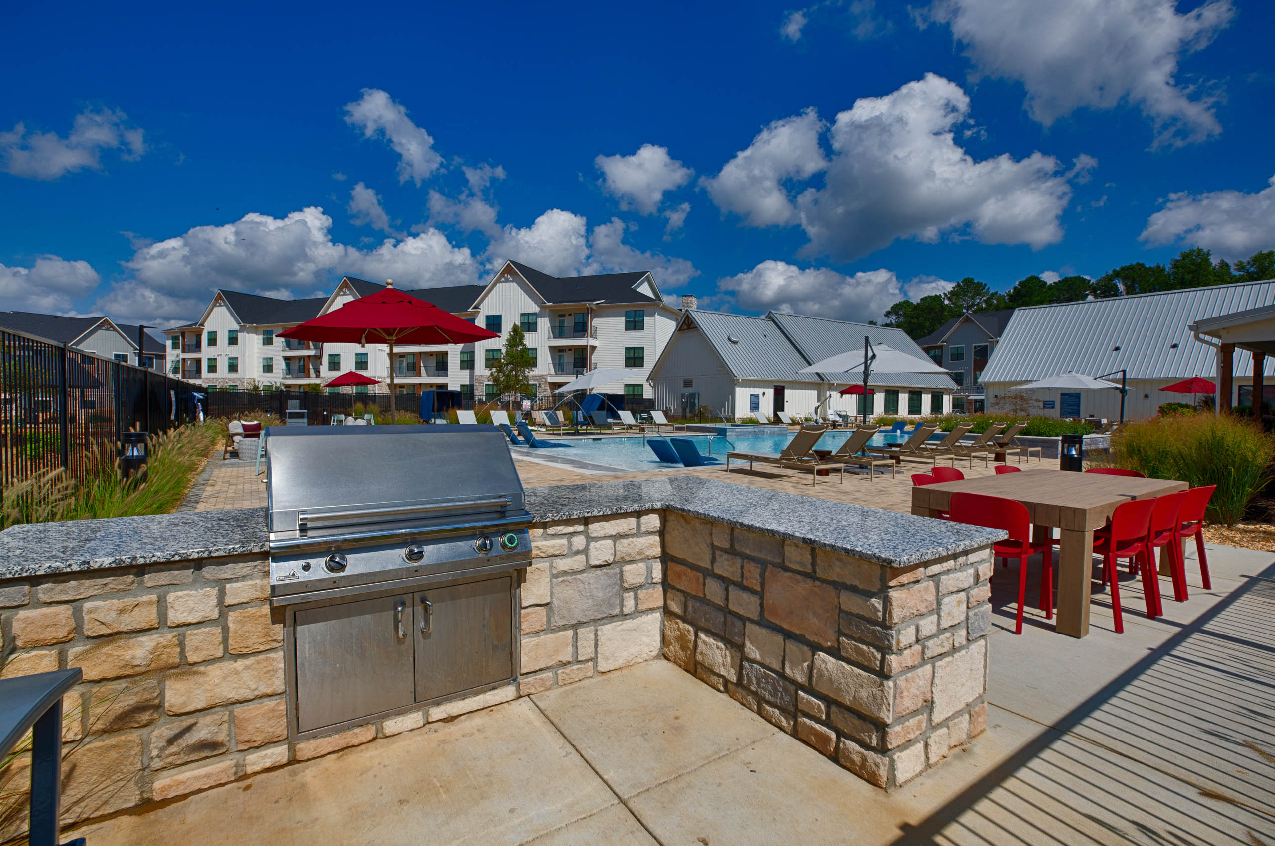 an outdoor kitchen with a grill and a table with chairs