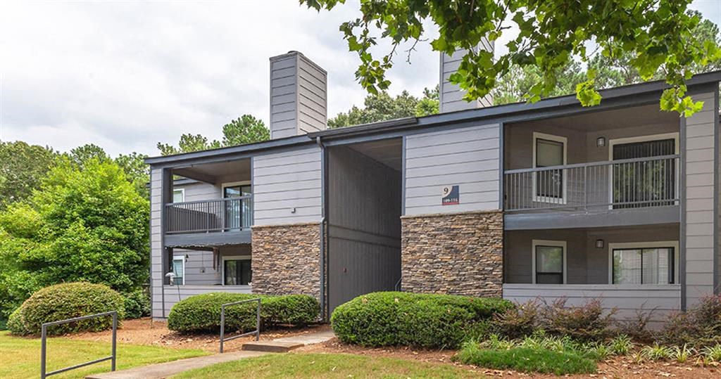 a white and gray apartment building with trees and bushes at High Ridge Apartments, Athens