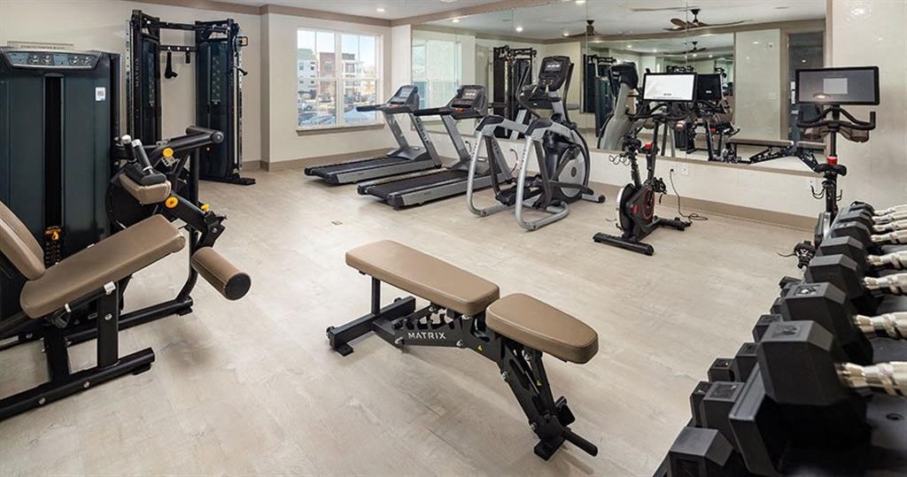 a gym with various exercise equipment on the floor and a window at The Flats at Southlawn Apartments, Lawrenceville, GA 30046