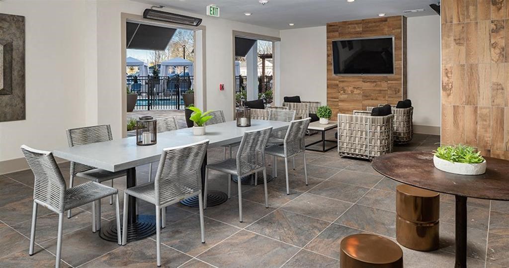 a dining room with tables and chairs and a television at The Flats at Southlawn Apartments, Lawrenceville, GA