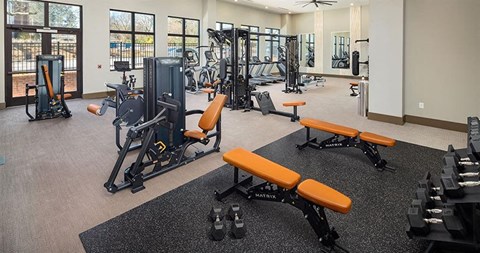 a gym with weights and other exercise equipment in a building at The Flats at Southlawn Apartments, Georgia