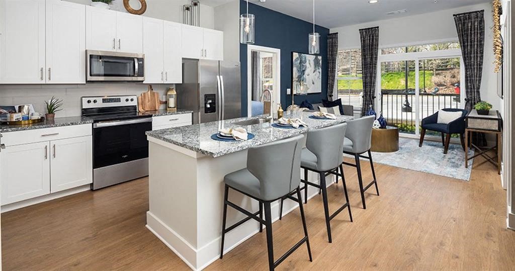 a kitchen with a large island with chairs at The Flats at Southlawn Apartments, Lawrenceville, 30046