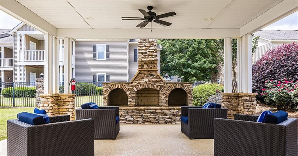 a covered patio with a stone fireplace and chairs at Bedford Parke Apartments, Warner Robins, GA 31088