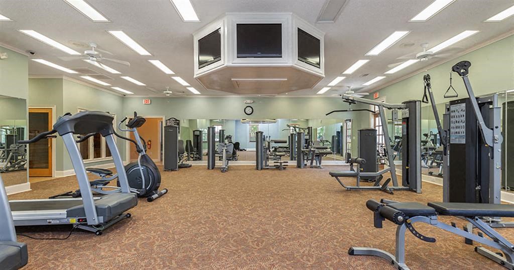 a gym with cardio machines and weights and a tv at Bedford Parke Apartments, Warner Robins