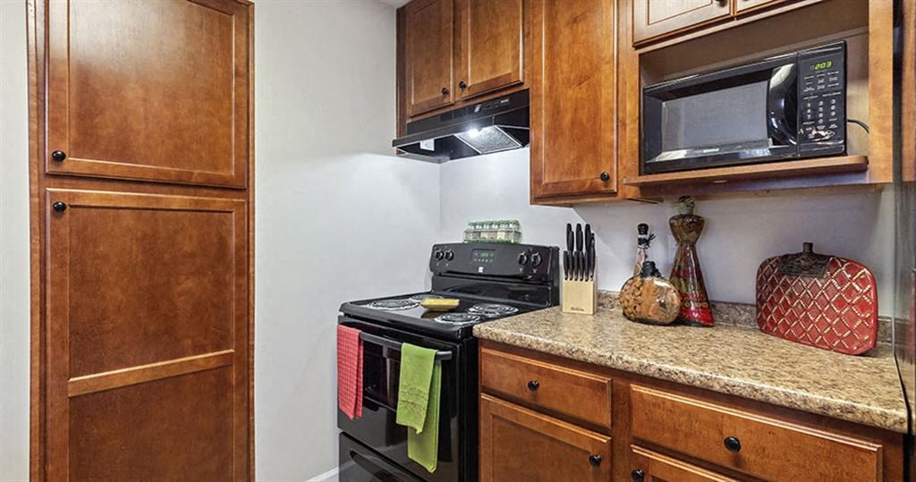 a kitchen with a stove and a microwave at Bedford Parke Apartments, Warner Robins