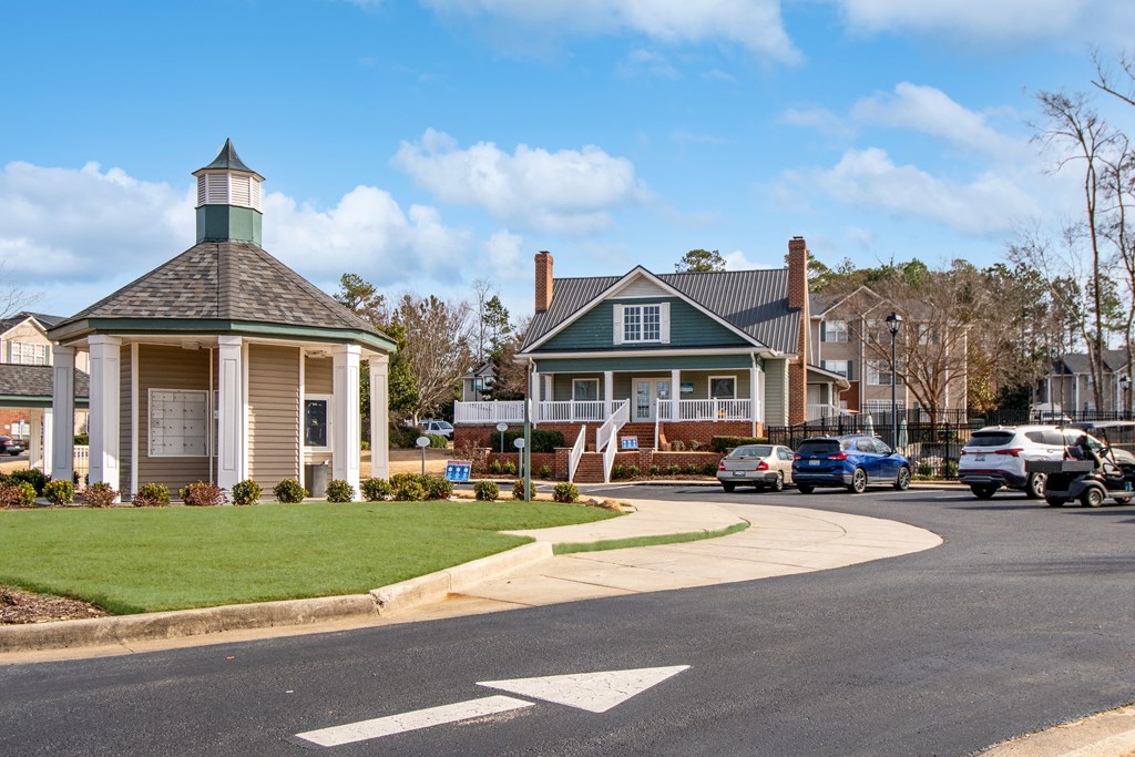 A small building with a green roof is in the middle of a road