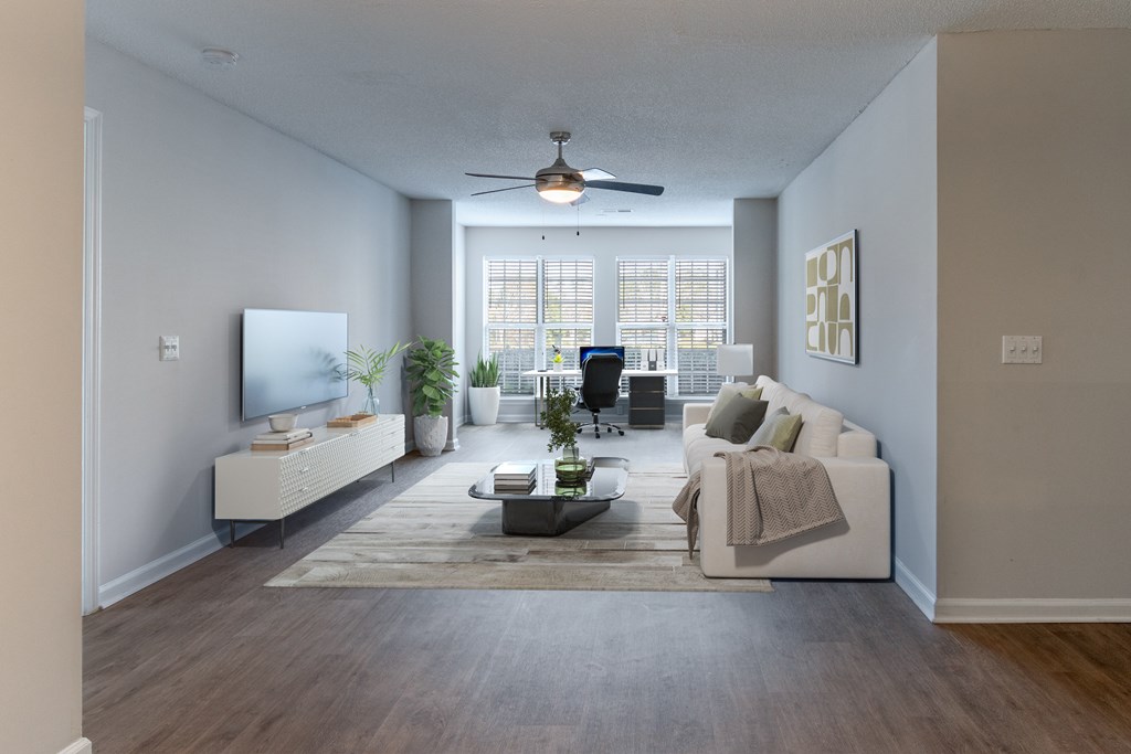 A living room with a white couch, a coffee table, and a television