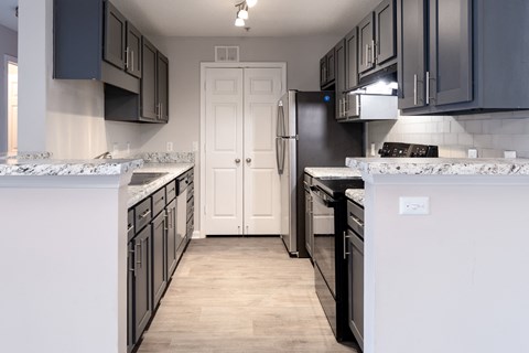 A kitchen with black cabinets and a white door.