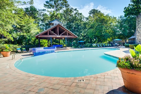 A pool surrounded by trees and a pavilion.
