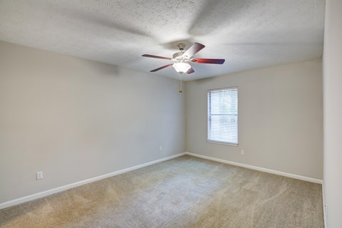 A room with a ceiling fan and carpeted floor.