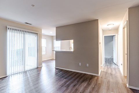 A spacious room with wooden floors and a large window with white curtains.