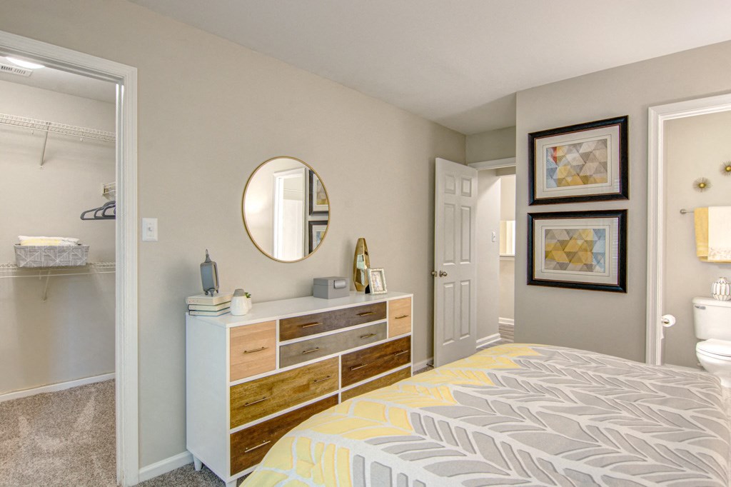 a bedroom with a bed and a dresser with a mirror on top of it at Hunters Chase Apartments, Midlothia