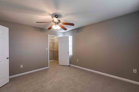 A room with a ceiling fan and carpeted floor.
