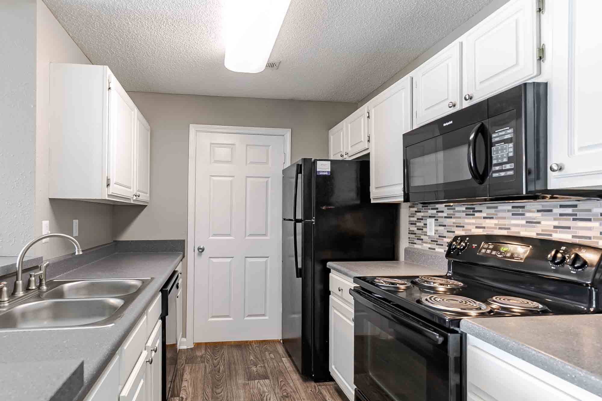 A kitchen with black appliances and white cabinets.