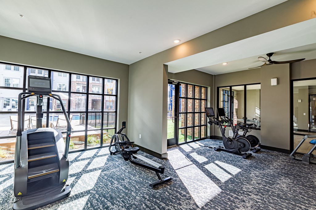 a gym with treadmills and weights in a room with windows at The Louis Apartment Flats, Louisville, Kentucky