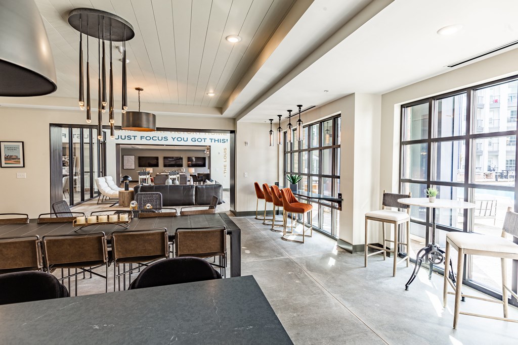 a communal area with tables and chairs and large windows at The Louis Apartment Flats, Louisville, Kentucky