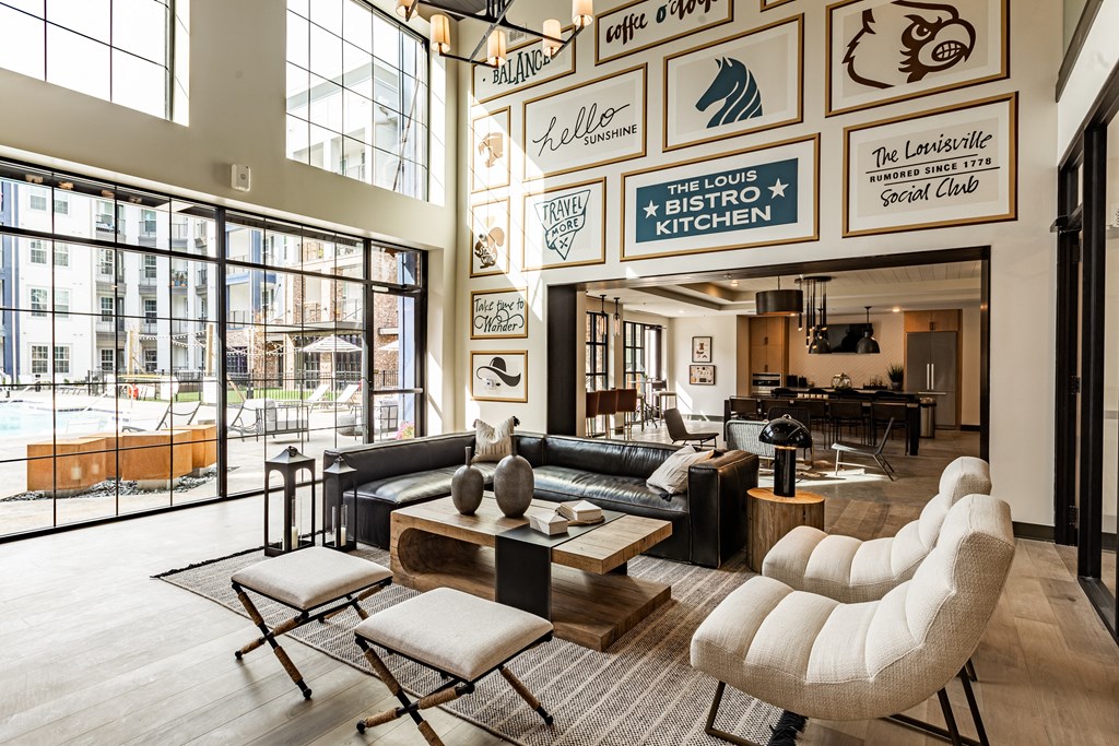 a living room with couches and tables and large windows at The Louis Apartment Flats, Louisville, KY