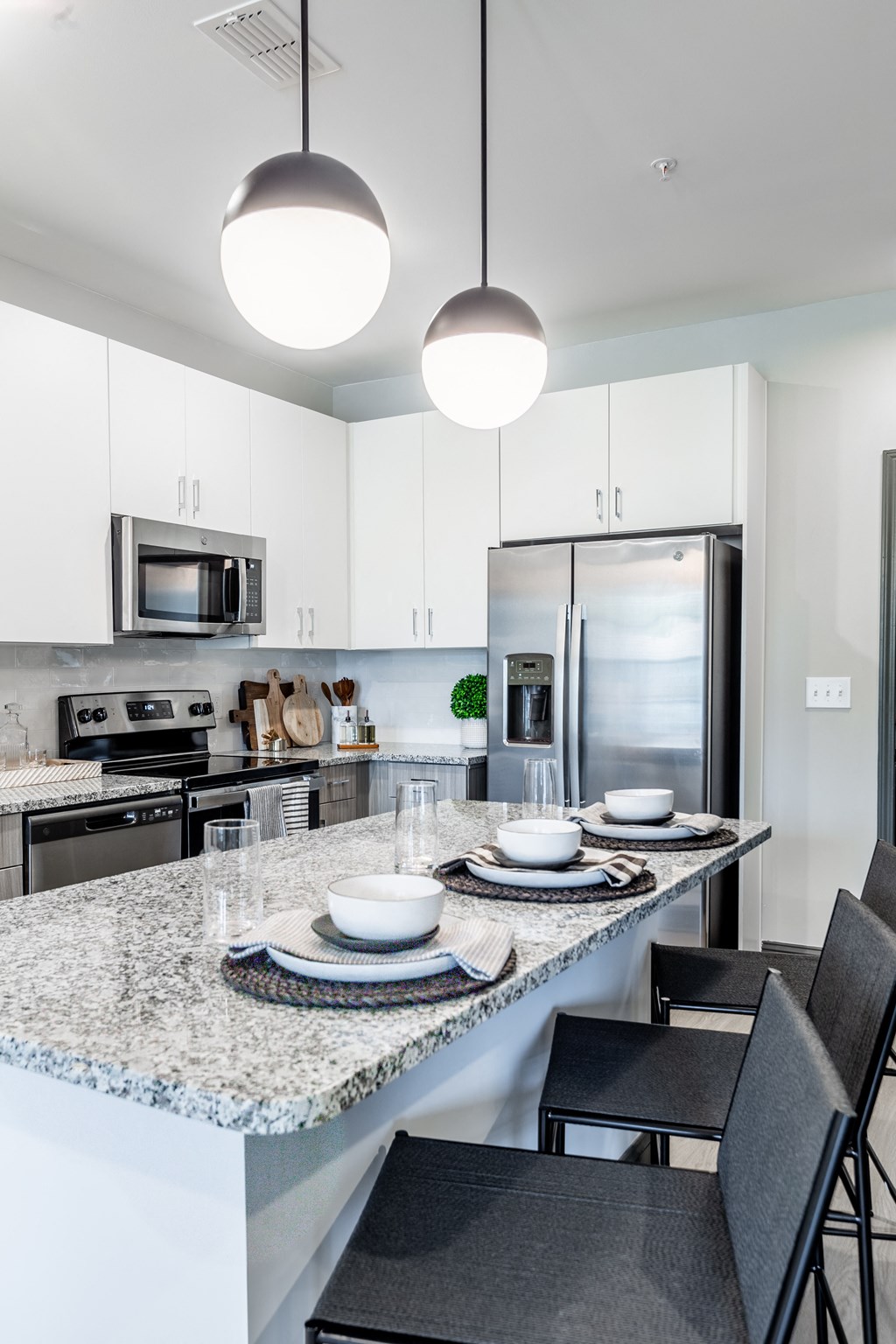 an open kitchen with a marble counter top and a large island with plates and bowls at The Louis Apartment Flats, Louisville, 40241