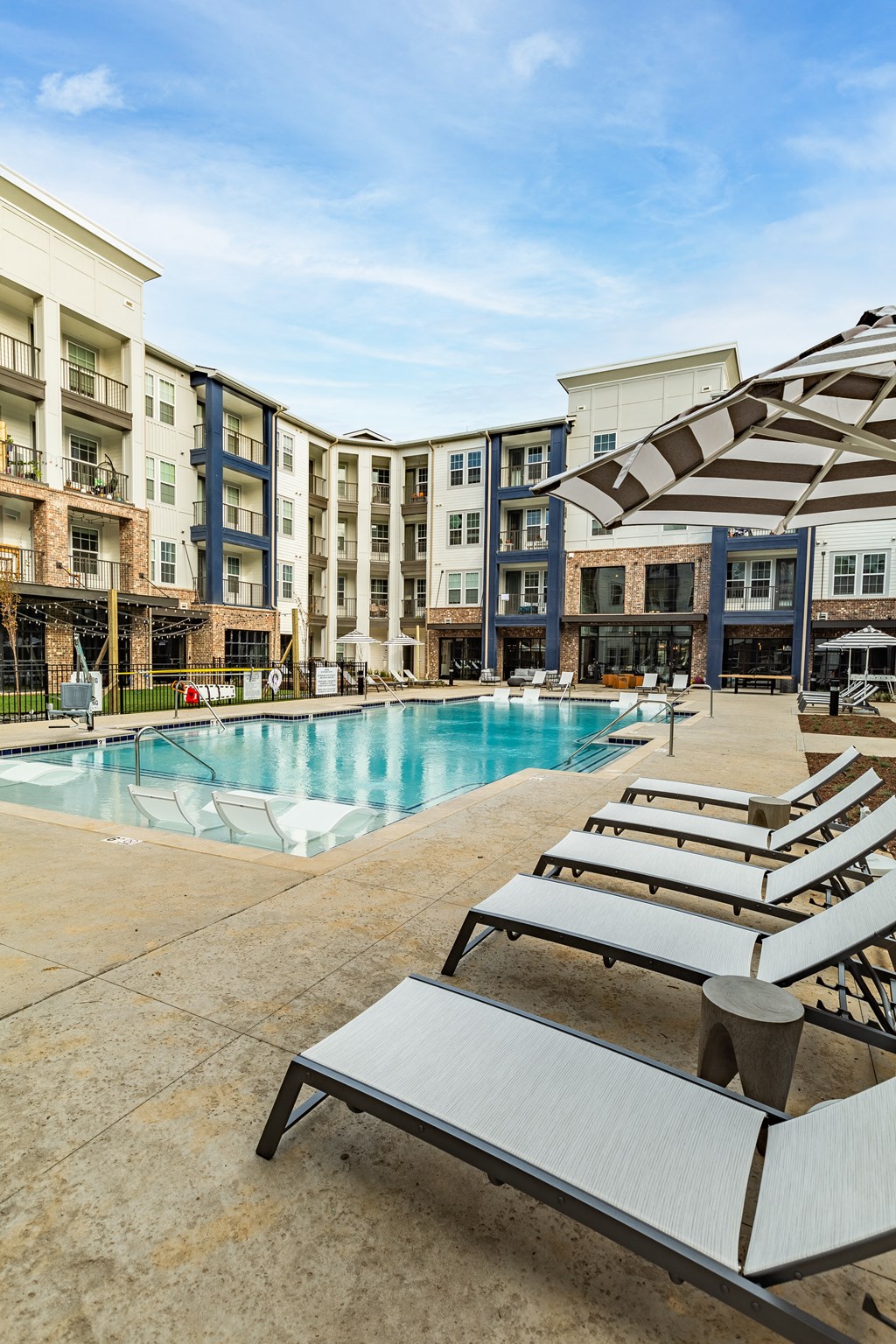 a swimming pool with beach chairs in front of an apartment building at The Louis Apartment Flats, Kentucky, 40241