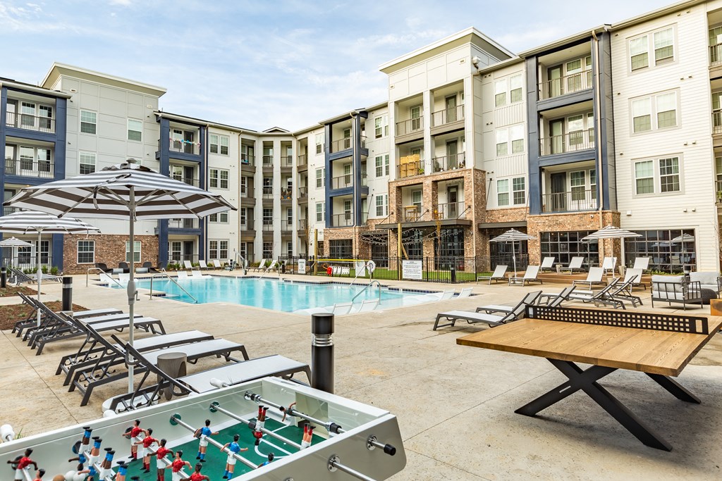 an outdoor pool with tables and chairs and an apartment building at The Louis Apartment Flats, Louisville